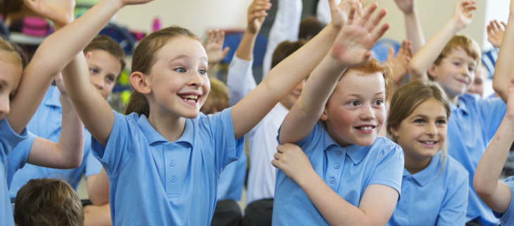 Excited School Children in Uniform with Hands Up